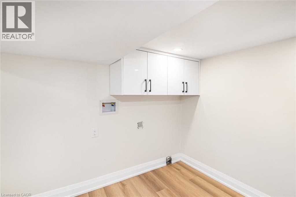 White shaker-style cabinetry with black hardware, recessed lighting, wood-finish flooring, and white baseboards - 250 Rosslyn Avenue N, Hamilton, ON