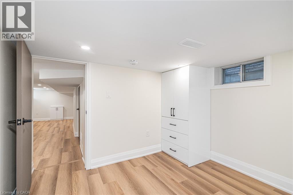 Wood-finish flooring, white built-in cabinetry with dark hardware, recessed lighting, and a white-framed window - 250 Rosslyn Avenue N, Hamilton, ON