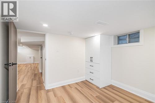 Wood-finish flooring, white built-in cabinetry with dark hardware, recessed lighting, and a white-framed window - 250 Rosslyn Avenue N, Hamilton, ON 