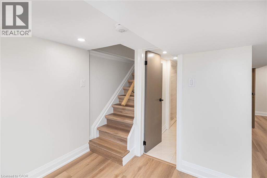 Recessed lighting, wood-finish flooring, staircase with wood treads, light gray interior door, and white trim - 250 Rosslyn Avenue N, Hamilton, ON