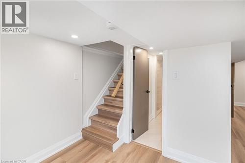 Recessed lighting, wood-finish flooring, staircase with wood treads, light gray interior door, and white trim - 250 Rosslyn Avenue N, Hamilton, ON 