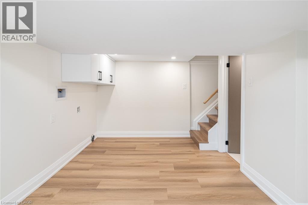 Bright interior space featuring wood-finish flooring, white walls, recessed lighting, and built-in white cabinetry with black hardware - 250 Rosslyn Avenue N, Hamilton, ON