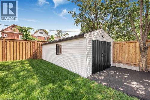 Detached garage with white vinyl siding, black panel garage door, and a single window - 250 Rosslyn Avenue N, Hamilton, ON 