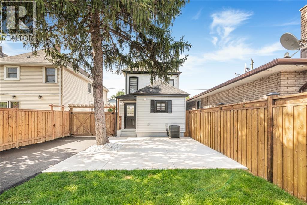 Private backyard featuring a concrete patio, manicured lawn, and wood privacy fencing - 250 Rosslyn Avenue N, Hamilton, ON