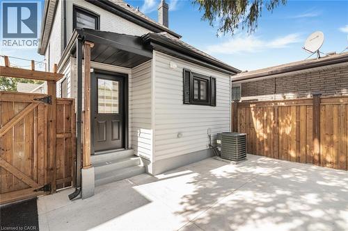 Exterior access with solid surface steps, a dark wood-finish gate, and light-colored siding - 250 Rosslyn Avenue N, Hamilton, ON 