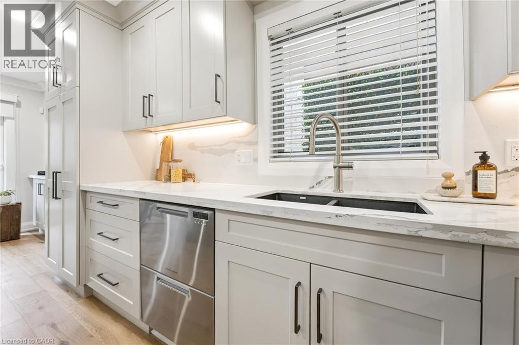 Light-toned wood-finish flooring complements custom shaker-style cabinetry with dark hardware - 1261 Stephenson Drive, Burlington, ON
