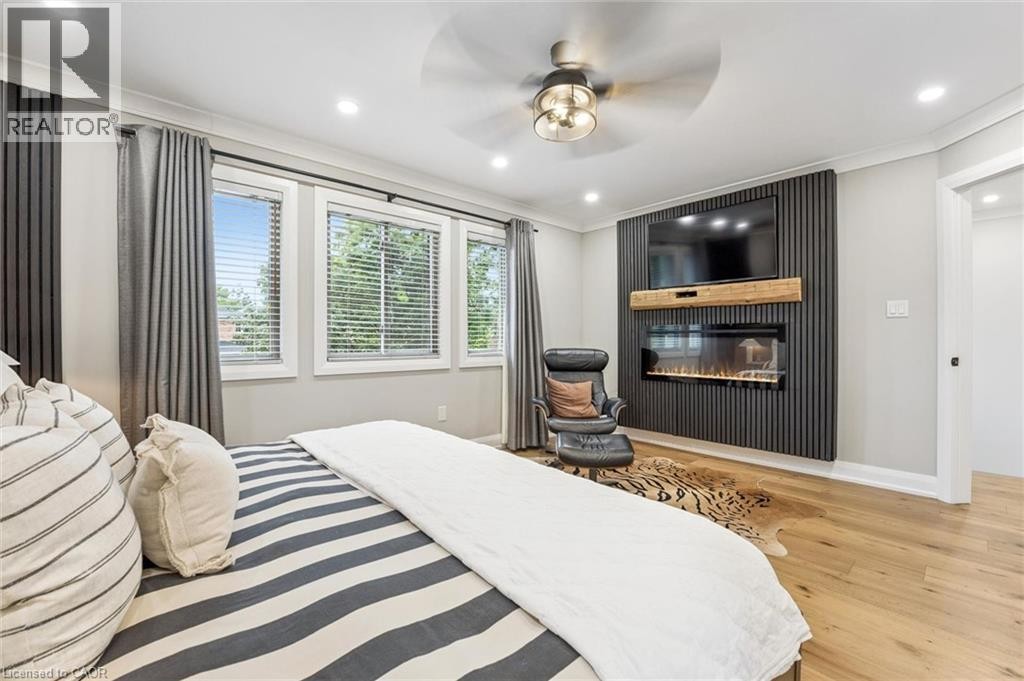 Hardwood-style flooring, a built-in electric fireplace, recessed lighting, and a ceiling fan with light fixture - 1261 Stephenson Drive, Burlington, ON