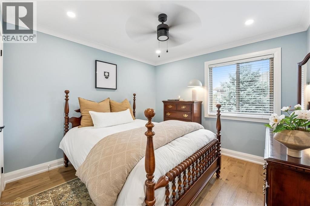 Wood-finish flooring, light blue wall paint, a window with blinds, a ceiling fan with integrated lighting, and recessed ceiling lights - 1261 Stephenson Drive, Burlington, ON