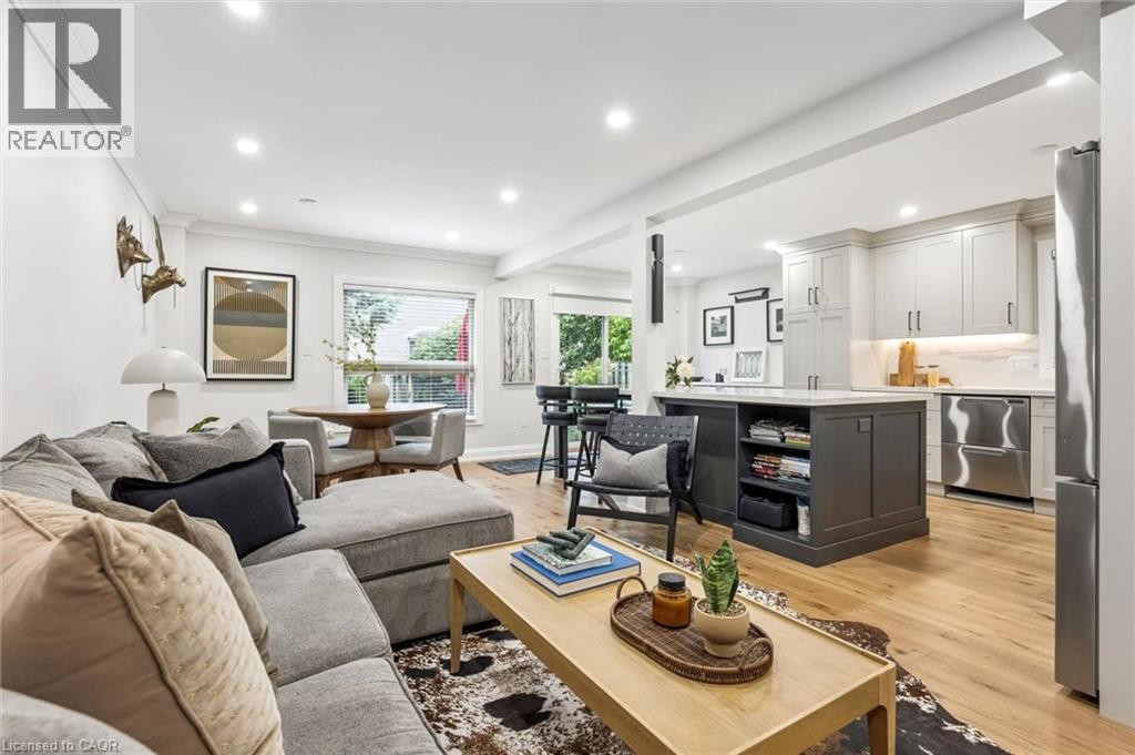 Open-concept living space featuring wood-finish flooring, recessed lighting, and a kitchen island with integrated shelving - 1261 Stephenson Drive, Burlington, ON
