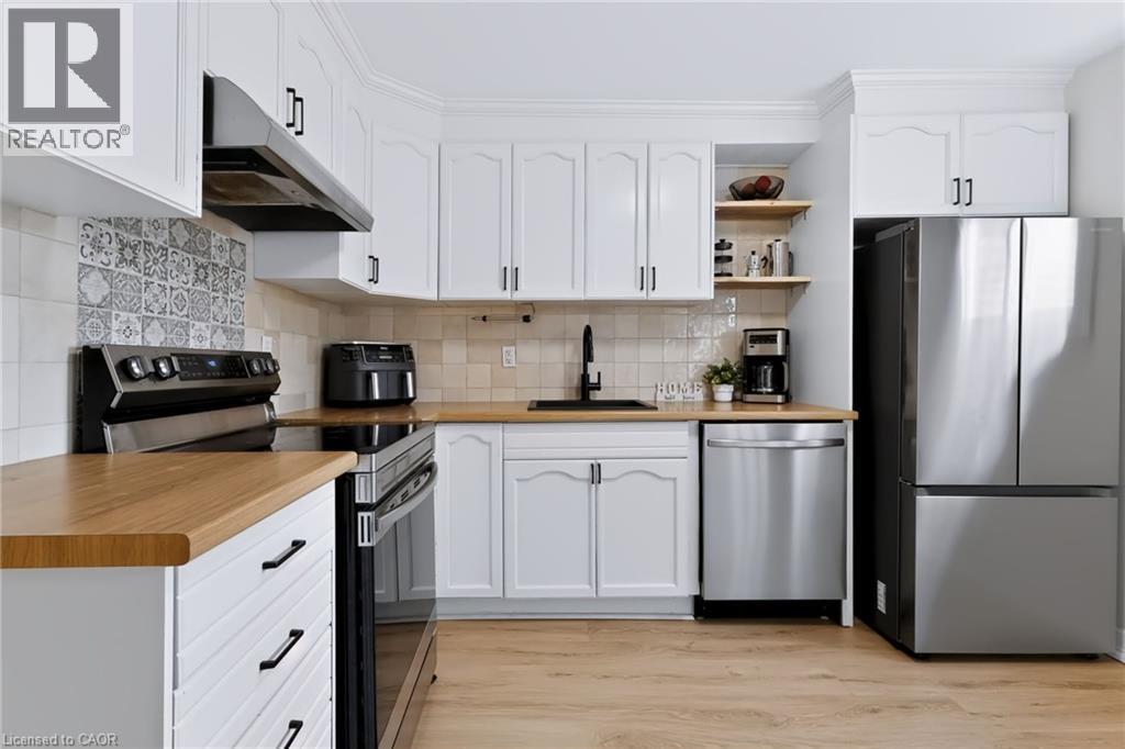 White cabinetry with crown molding, wood-finish countertops, stainless steel appliances, and wood-finish flooring - 34 Baillie Street, Hamilton, ON