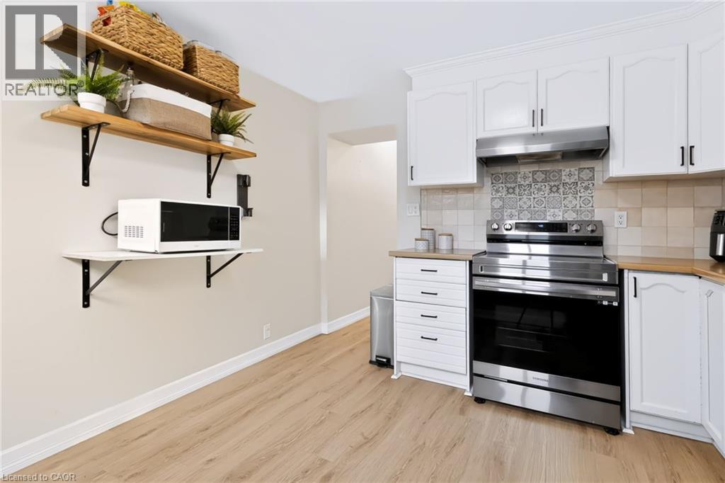 Light wood-finish flooring complements the white cabinetry - 34 Baillie Street, Hamilton, ON