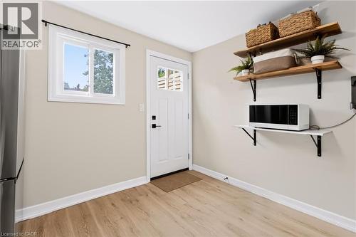 Light wood-finish flooring, white trim, and a white paneled door with multi-pane window - 34 Baillie Street, Hamilton, ON 