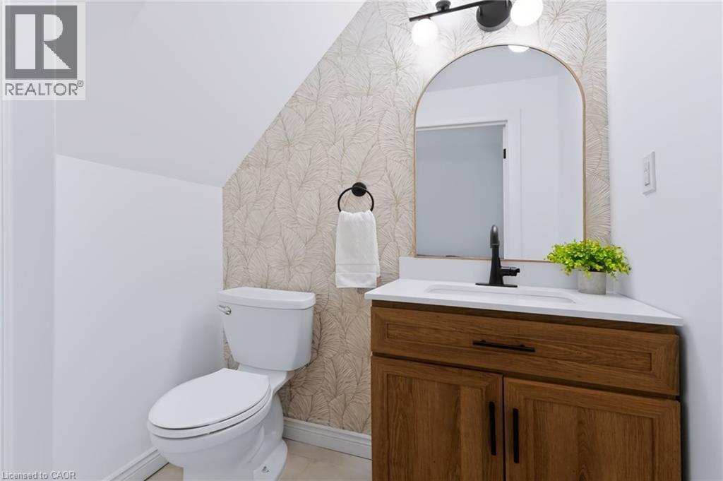 White vanity with a wood-finish cabinet, white countertop, and matte black faucet - 34 Baillie Street, Hamilton, ON