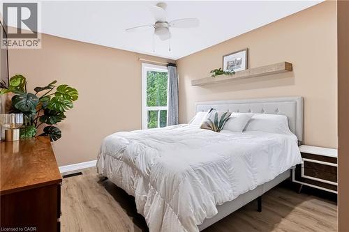 Wood-finish flooring, ceiling fan, window with exterior scenery, built-in wall shelf, and upholstered headboard - 34 Baillie Street, Hamilton, ON 