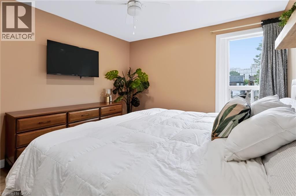 White ceiling fan, neutral wall tones, large window with natural light, window treatments, wood-finish dresser - 34 Baillie Street, Hamilton, ON