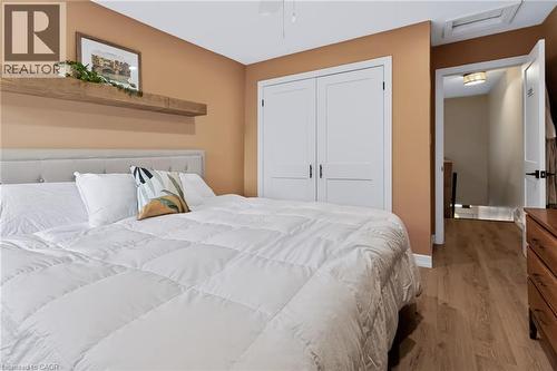 Wood-finish flooring with a neutral wall color, white double-door closet, and a light gray tufted headboard - 34 Baillie Street, Hamilton, ON 