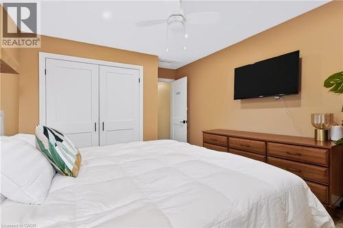 Room featuring a ceiling fan, light-colored walls, and a wall-mounted television - 34 Baillie Street, Hamilton, ON 