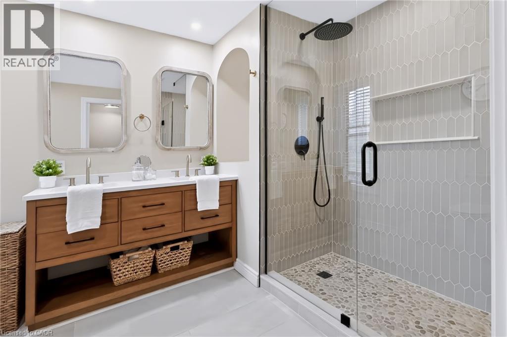 Dual vanity with solid surface countertop, wood-finish cabinetry, and framed mirrors - 34 Baillie Street, Hamilton, ON