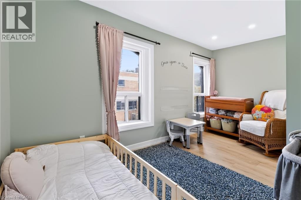Recessed lighting, light green wall finishes, wood-finish flooring, and two windows with white trim - 34 Baillie Street, Hamilton, ON