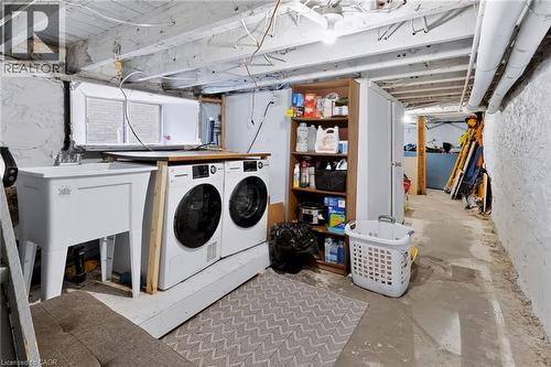 Laundry area featuring a utility sink, front-load washer and dryer, and built-in shelving - 34 Baillie Street, Hamilton, ON 
