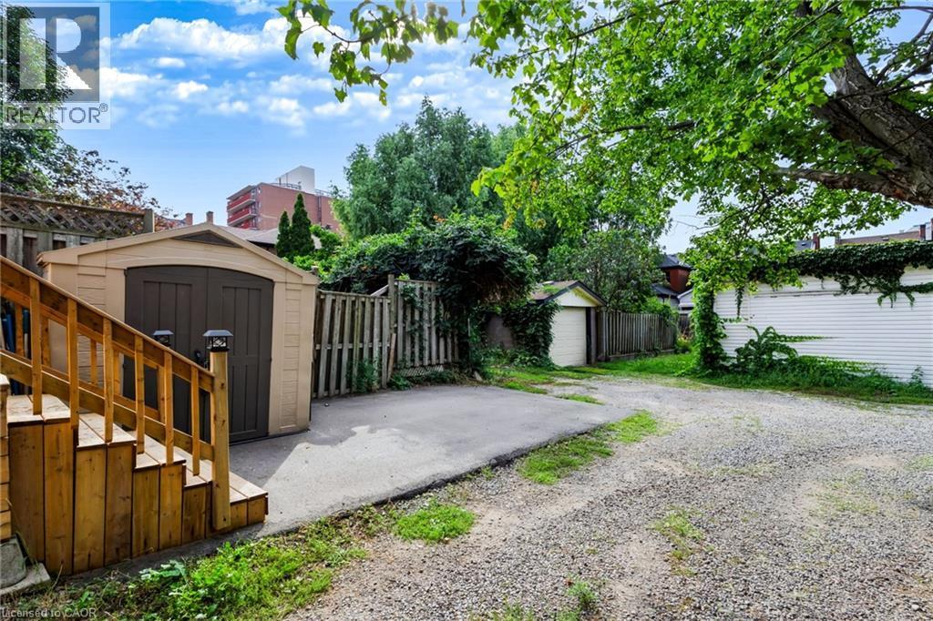 Wooden exterior staircase with railing, leading to a compact storage shed with double doors - 34 Baillie Street, Hamilton, ON