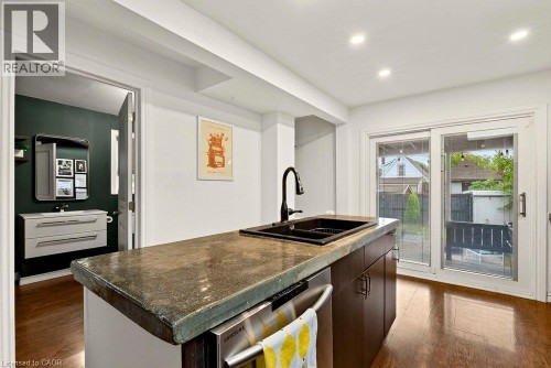 Kitchen island with an undermount sink, dark wood-finish cabinetry, and a stainless steel dishwasher - 136 Weir Street N, Hamilton, ON 