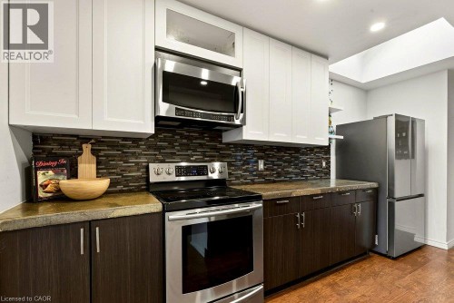 Stainless steel appliances, mosaic tile backsplash, wood-finish flooring, two-tone cabinetry, and a skylight feature - 136 Weir Street N, Hamilton, ON 