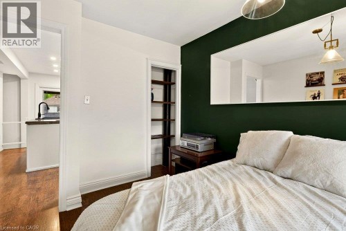 Richly painted accent wall, built-in shelving, laminate flooring, and recessed lighting - 136 Weir Street N, Hamilton, ON 