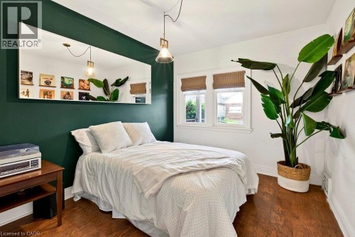 Laminate flooring throughout, dual windows with natural light, a rectangular wall-mounted mirror, and an overhead pendant light fixture - 136 Weir Street N, Hamilton, ON 