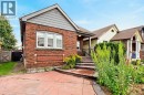 Brick exterior with a gabled roofline, stone window sills, and a concrete driveway - 136 Weir Street N, Hamilton, ON 
