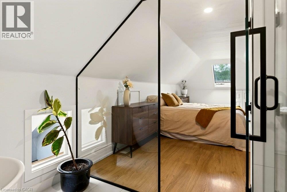 Attic space with sloped ceilings, laminate flooring, and a skylight - 136 Weir Street N, Hamilton, ON