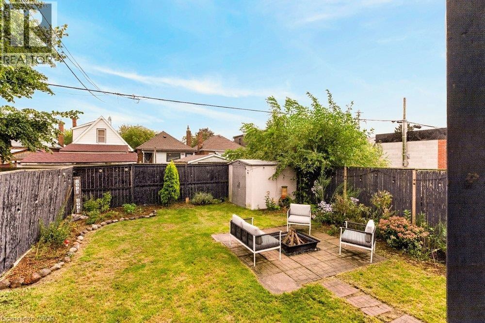 Expansive backyard featuring a manicured lawn, established landscaping, and a paver patio - 136 Weir Street N, Hamilton, ON