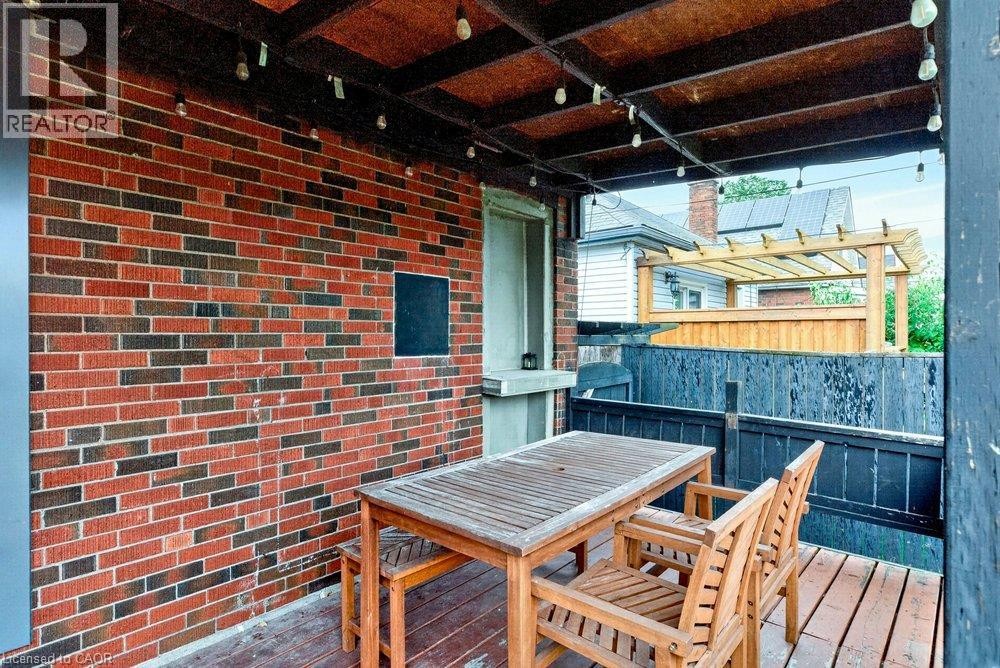 Covered outdoor patio with exposed beam ceiling, brick wall, and wood-finish flooring - 136 Weir Street N, Hamilton, ON