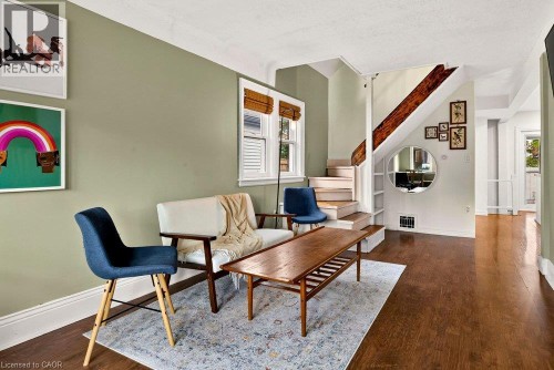 Laminate flooring throughout, painted walls, white trim, and a staircase with a wood handrail - 136 Weir Street N, Hamilton, ON 