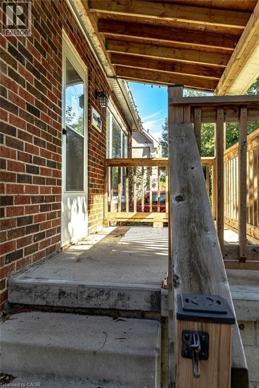 Brick exterior with a covered wooden porch and concrete steps - 860 Garth Street, Hamilton, ON