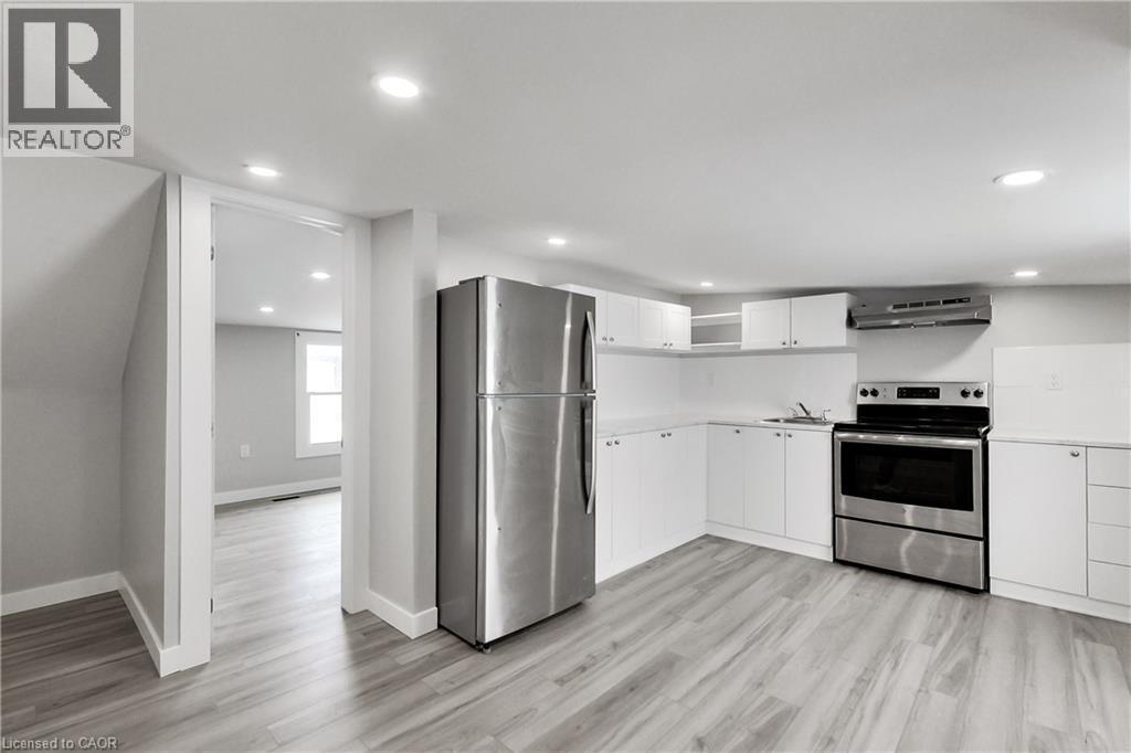 Kitchen with wood-finish flooring, white cabinetry, stainless steel appliances, and recessed lighting - 229 Parkdale Avenue N, Hamilton, ON