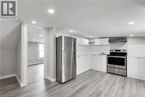 Kitchen with wood-finish flooring, white cabinetry, stainless steel appliances, and recessed lighting - 229 Parkdale Avenue N, Hamilton, ON 