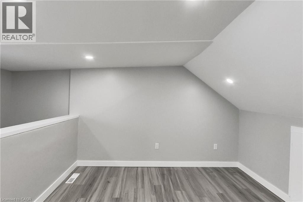 Sloped ceiling with recessed lighting, wood-finish flooring, and a low wall partition - 229 Parkdale Avenue N, Hamilton, ON