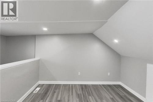 Sloped ceiling with recessed lighting, wood-finish flooring, and a low wall partition - 229 Parkdale Avenue N, Hamilton, ON 