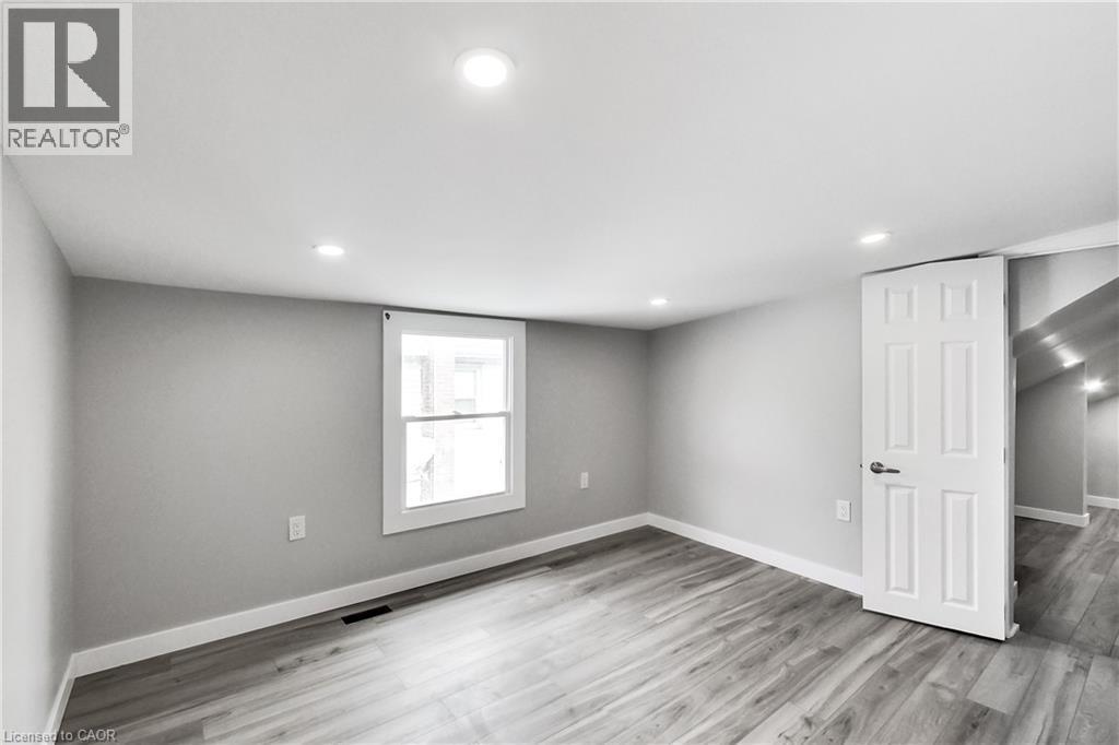 Recessed ceiling lighting, wood-finish flooring, white trim, and a paneled interior door - 229 Parkdale Avenue N, Hamilton, ON