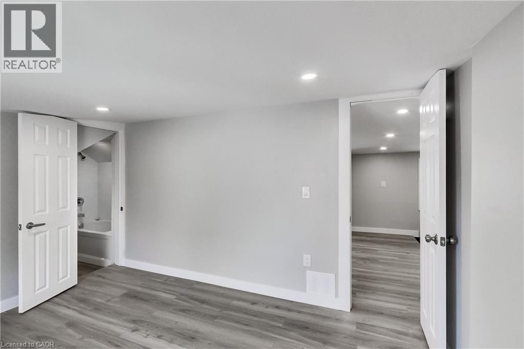 Wood-finish flooring throughout, recessed ceiling lighting, light gray wall finish, and white six-panel interior doors - 229 Parkdale Avenue N, Hamilton, ON
