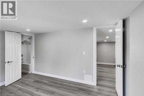Wood-finish flooring throughout, recessed ceiling lighting, light gray wall finish, and white six-panel interior doors - 229 Parkdale Avenue N, Hamilton, ON 
