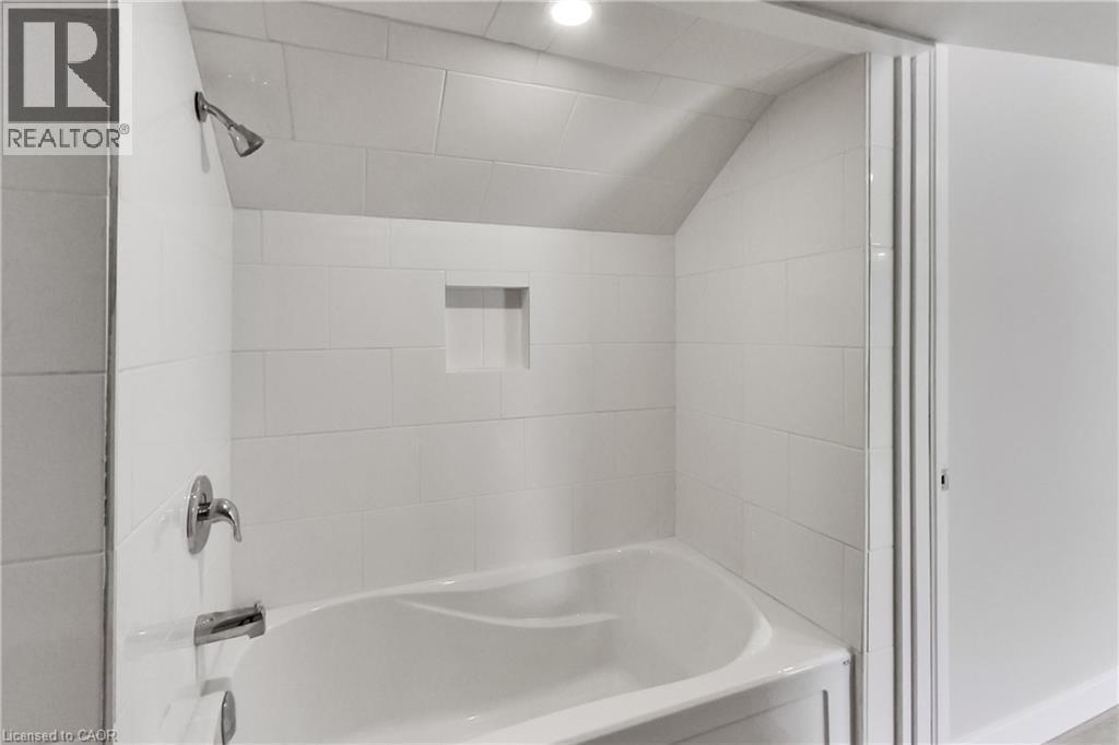 White tiled shower with a built-in niche and chrome fixtures - 229 Parkdale Avenue N, Hamilton, ON