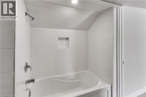 White tiled shower with a built-in niche and chrome fixtures - 229 Parkdale Avenue N, Hamilton, ON 
