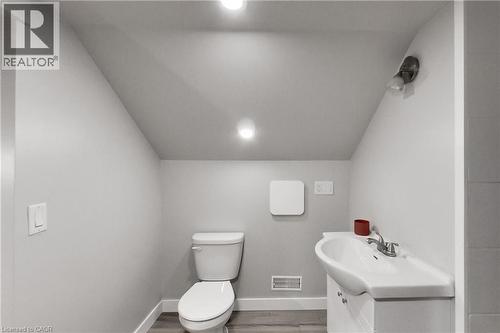 Recessed ceiling lighting, angled ceiling, white toilet, wall-mounted vanity light, wood-finish flooring - 229 Parkdale Avenue N, Hamilton, ON 