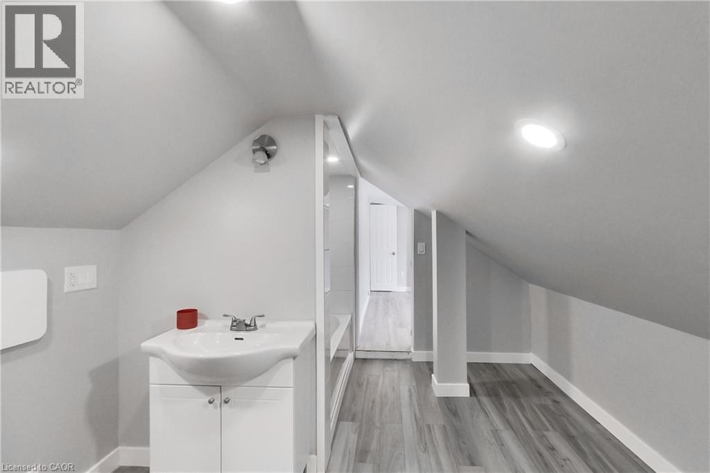 Sloped ceilings, recessed lighting, wood-finish flooring, white vanity with integrated sink, and chrome fixtures - 229 Parkdale Avenue N, Hamilton, ON
