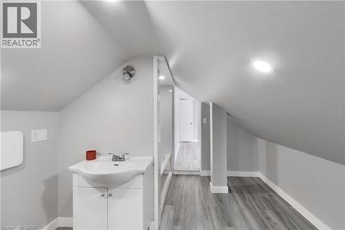 Sloped ceilings, recessed lighting, wood-finish flooring, white vanity with integrated sink, and chrome fixtures - 229 Parkdale Avenue N, Hamilton, ON 