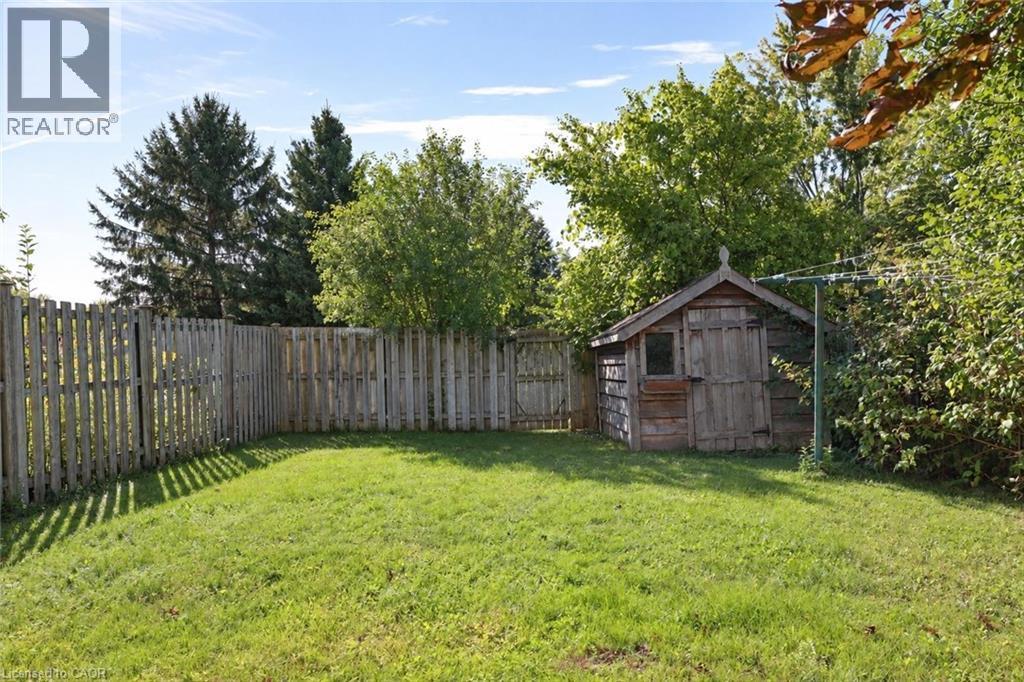 Expansive backyard featuring a manicured lawn, complete wood privacy fencing, a functional wooden shed, and mature perimeter trees - 95 Resurrection Drive, Kitchener, ON
