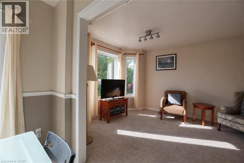 Spacious living area with dual glass doors providing natural light, carpeted flooring throughout, and entertainment-ready layout with television mounting - 95 Resurrection Drive, Kitchener, ON
