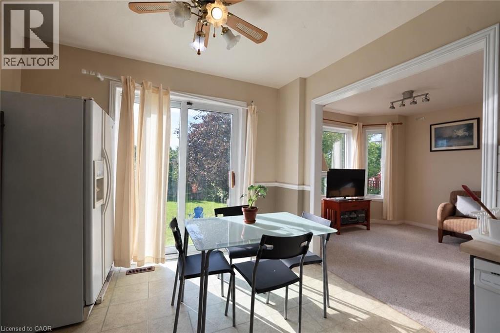 Kitchen with tile flooring and a ceiling fan, featuring a stainless steel refrigerator and a sliding glass door to the exterior - 95 Resurrection Drive, Kitchener, ON